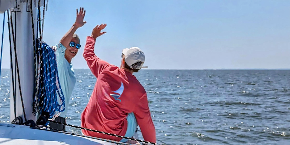 Two sailors sharing a high five while sailing on the Chesapeake Bay